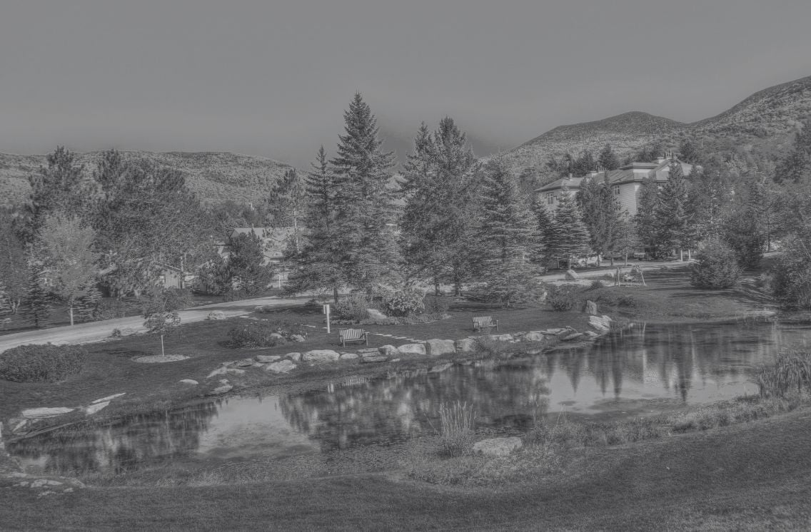Scenic landscape with trees, mountains, and a reflective pond near modern buildings, symbolizing clarity and insights for AI marketing analytics