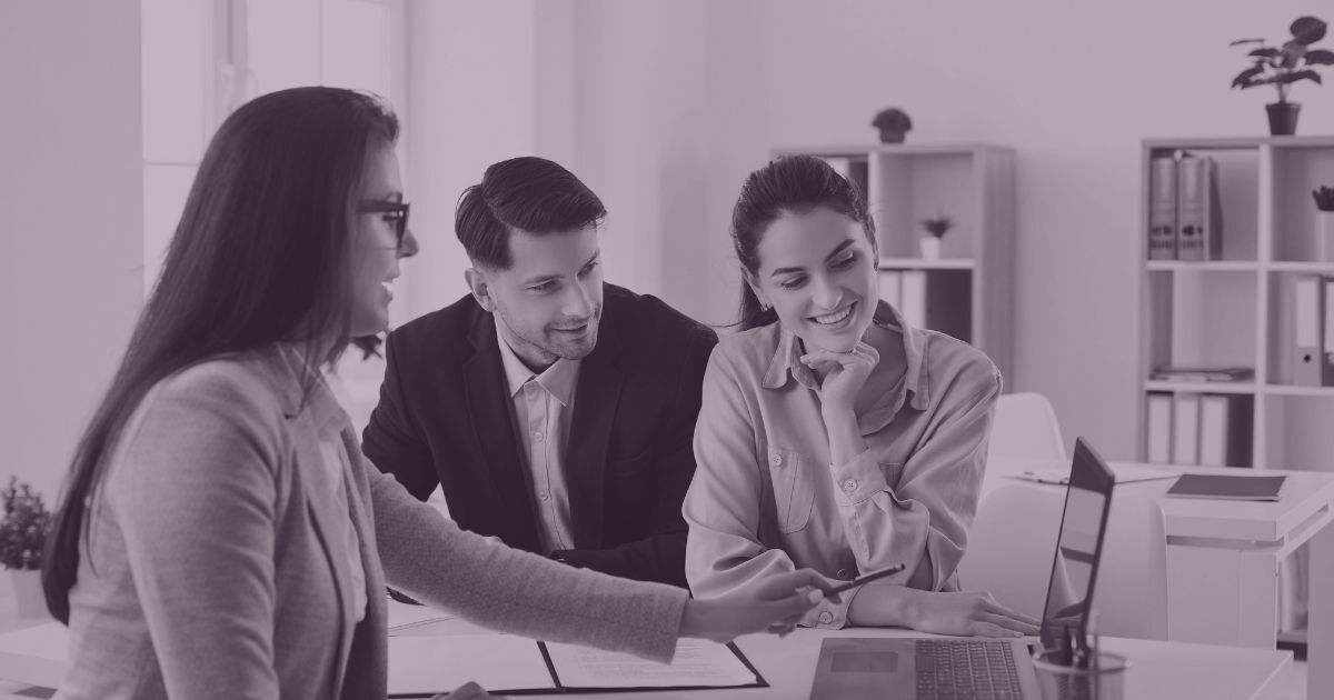 Business professionals collaborating on a laptop during a client meeting.