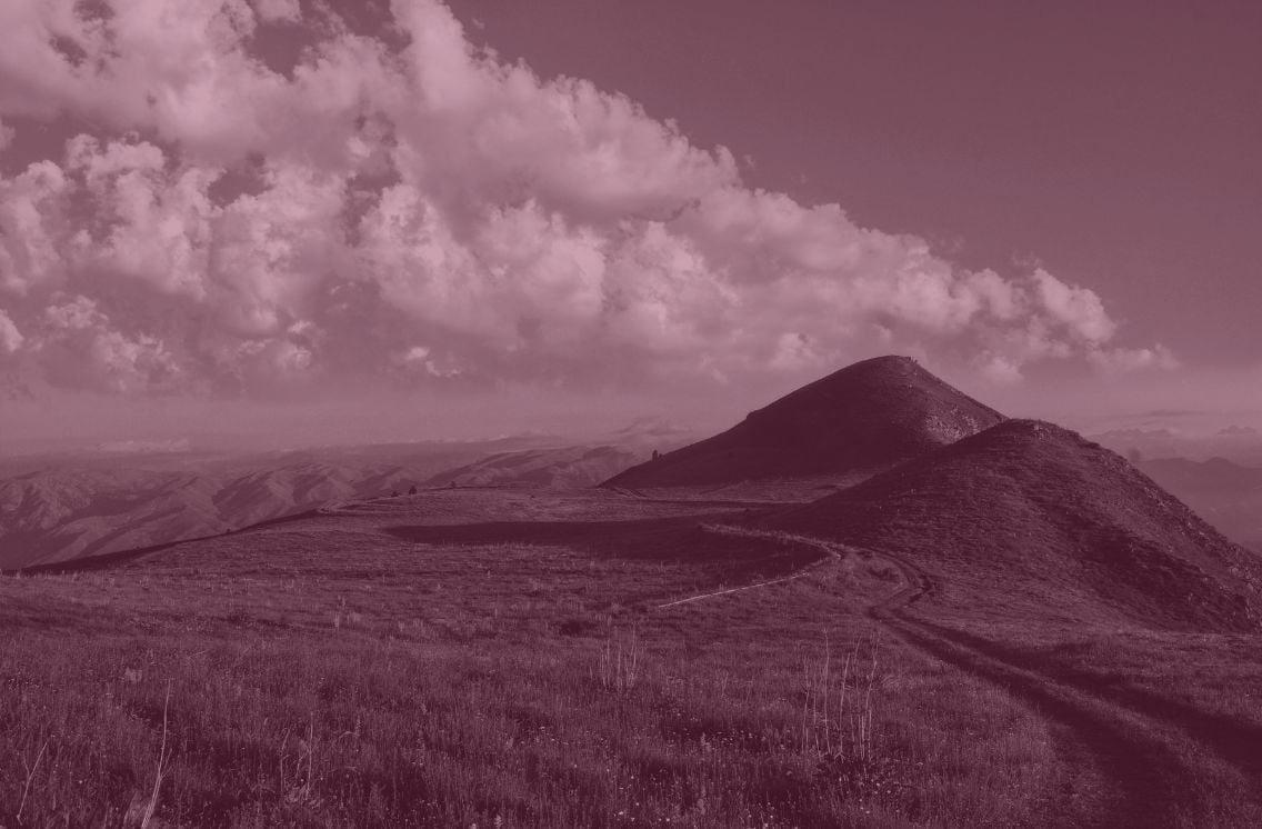 Grassy mountain path leading toward two peaks under a dramatic sky, symbolizing the journey toward ethical and transparent AI marketing practices